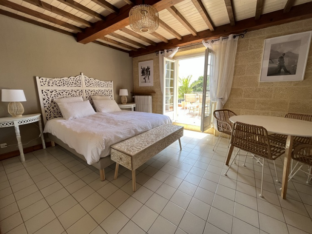 Cette image présente la chambre 1 de la chambre d'hôte Sean Connery du Temps des Légendes. Elle est composée d'1 lit de 180 x 200 cm. La chambre est équipée d'une table, 2 chaises et 2 fauteuils et d'un grand dressing. Elle donne accès à la terrasse privative.