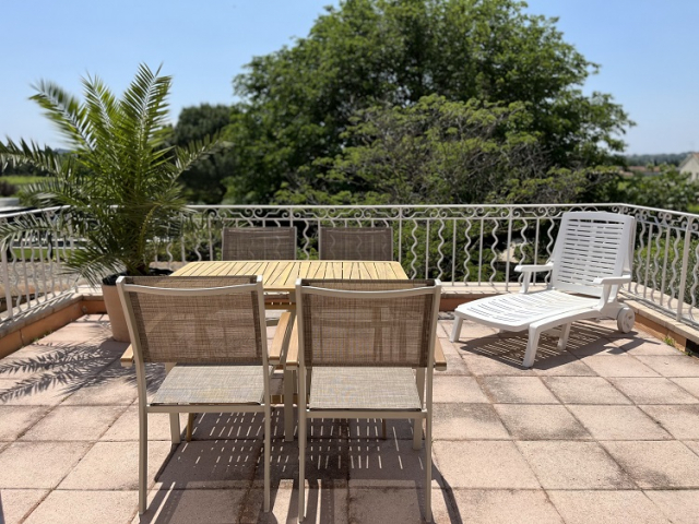 Cette image présente la terrasse de la chambre d'hôte Sean Connery du Temps des Légendes. Elle est équipée d'une table, 4 fauteuils, d'un parasol déporté, elle est végétalisée et donne sur le parc arboré.