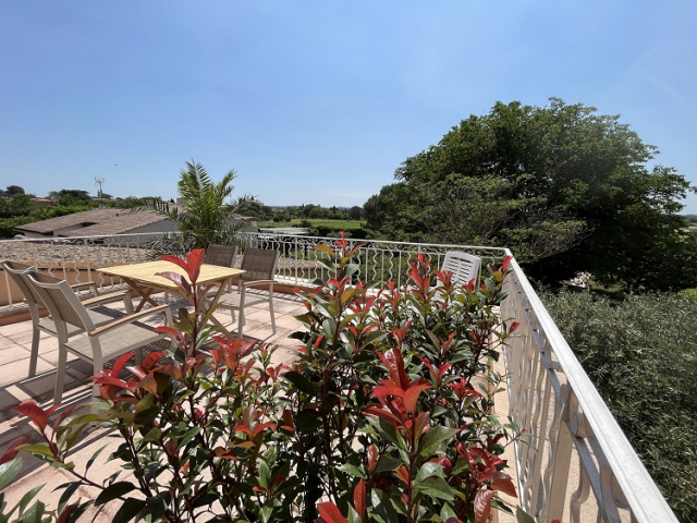 Cette image présente la terrasse de la chambre d'hôte Sean Connery du Temps des Légendes. Elle est équipée d'une table, 4 fauteuils, d'un parasol déporté, elle est végétalisée et donne sur le parc arboré.