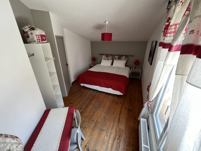 Cette image présente la 1ère chambre de l'étage. Cette chambre spacieuse et lumineuse est composée d'un lit 180x200 cm avec 2 tables de nuits et ses lampes de chevets, d'un bureau avec sa chaise et d'une lampe sur pieds.