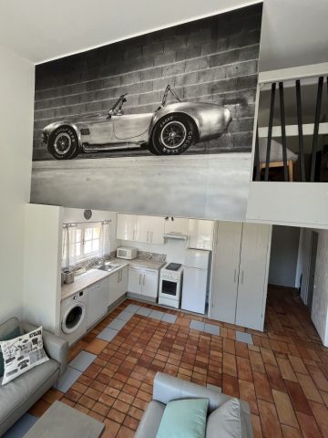 Cuisine ouverte équipée et fonctionnelle Cette image présente le séjour lumineux de 41m2 du gîte Shelby de Le Temps des Légendes, comportant une agréable cuisine équipée et fonctionnelle, un confortable salon télévision avec ses 2 canapés cuirs 3 places, ainsi qu'un espace repas style industriel pour 6 personnes.