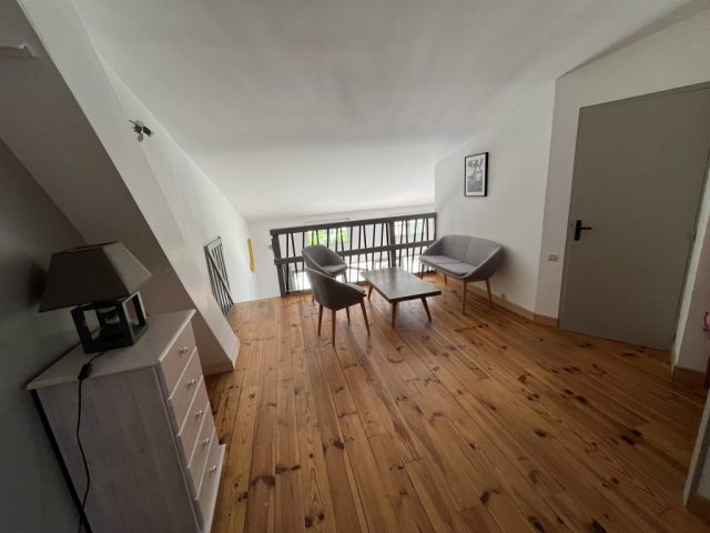 Cette image présente la mezzanine, avec son espace détente lecture, comportant un chiffonnier et u ne bibliothèque.