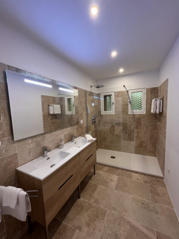 Cette image présente la salle d'eau de la chambre d'hôte Sean Connery du Temps des Légendes. Elle est composée d'une grande douche italienne et d'un meuble 2 vasques.