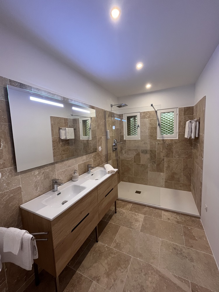 Cette image présente la salle d'eau de la chambre d'hôte Sean Connery du Temps des Légendes. Elle est composée d'une grande douche italienne et d'un meuble 2 vasques.