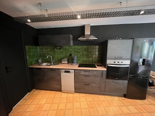 Cette image représente la cuisine intégrée du gîte Berlinette. De style industriel, elle offre un panel complet d'électroménagers modernes.