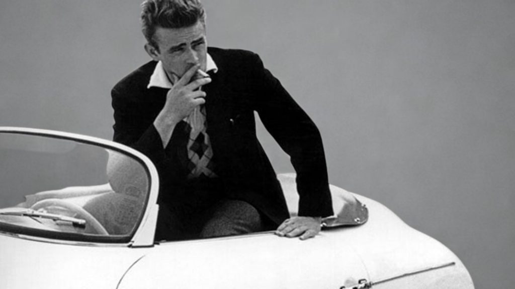 Cette image représente l'acteur James Dean assis sur Porsche 550 Spyder surnommée "Little Bastard"