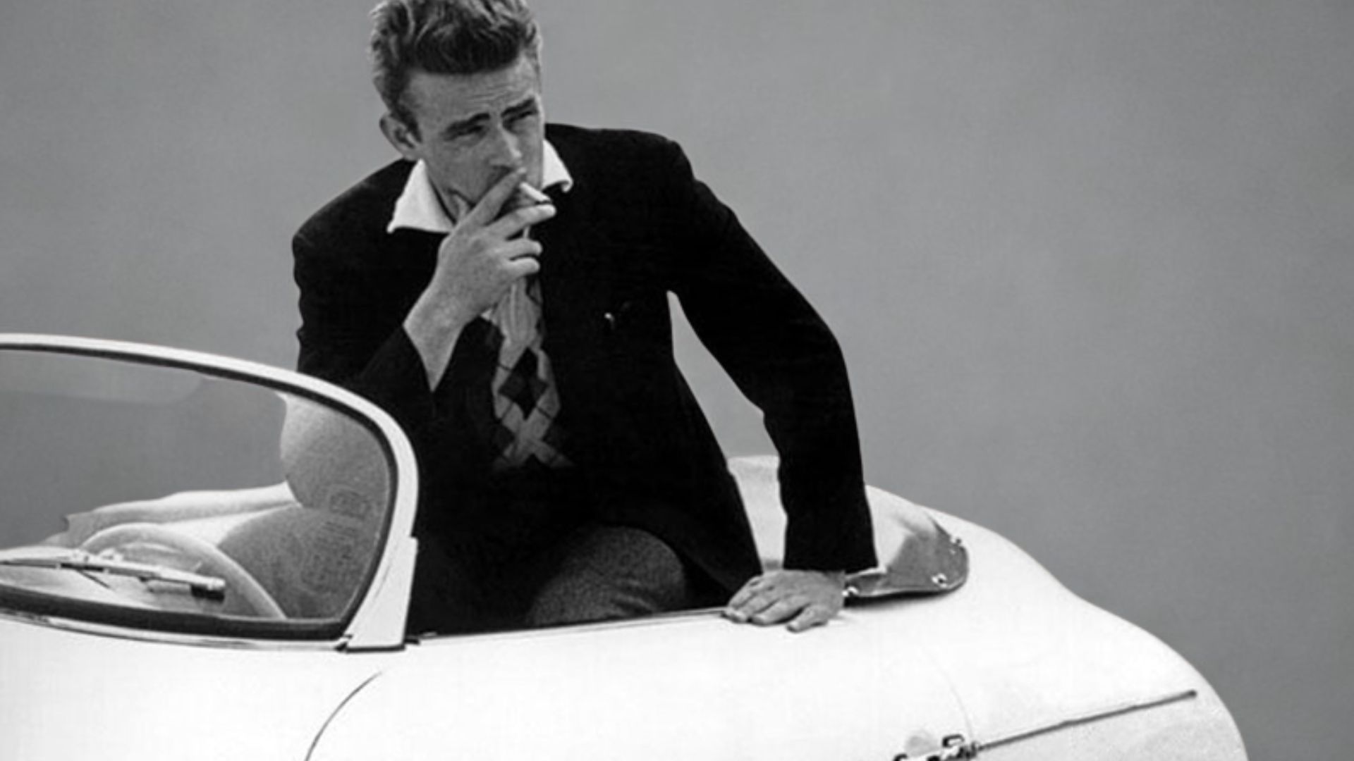 Cette image représente l'acteur James Dean assis sur Porsche 550 Spyder surnommée "Little Bastard"