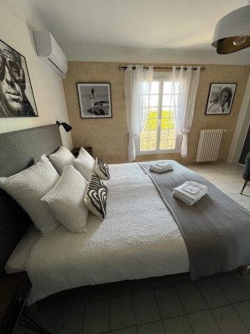 Cette image présente la chambre d'hôte Steve McQueen du Temps des Légendes. Elle est composée d'1 lit de 180 x 200 cm. La chambre est équipée d'une table, 2 fauteuils, d'un bureau avec fauteuil et d'un grand dressing.