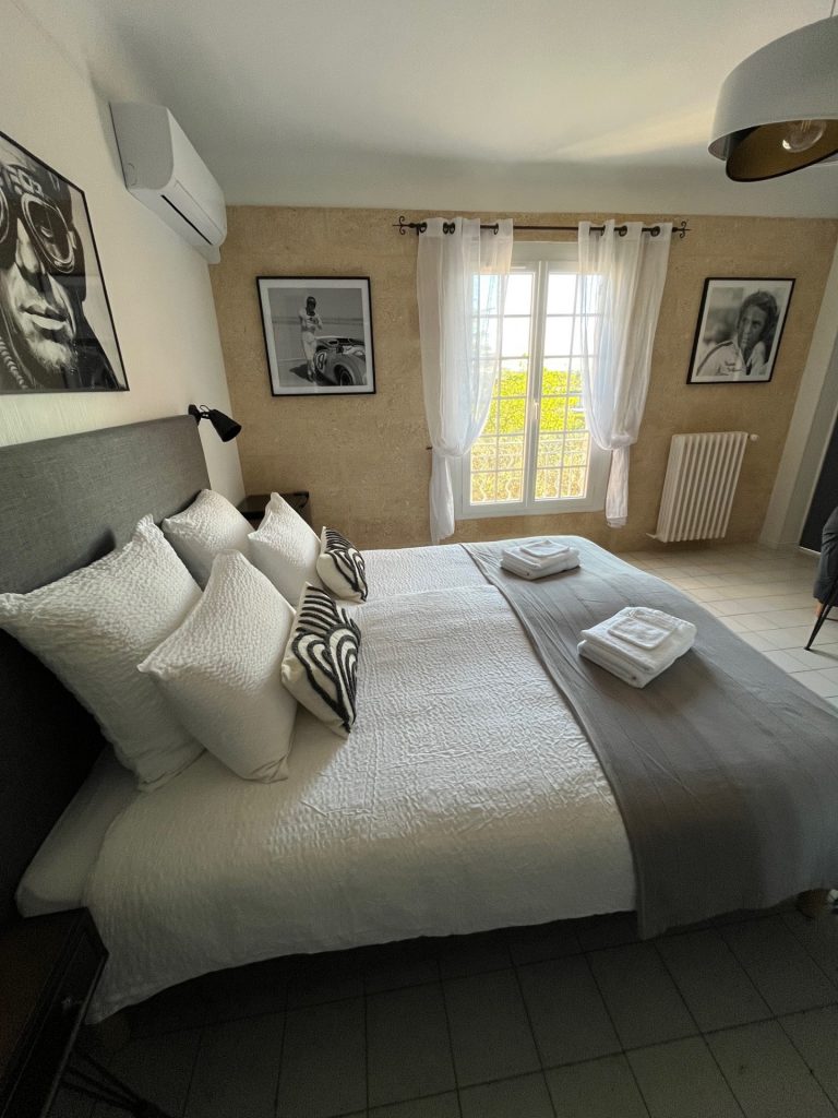 Cette image présente la chambre d'hôte Steve McQueen du Temps des Légendes. Elle est composée d'1 lit de 180 x 200 cm. La chambre est équipée d'une table, 2 fauteuils, d'un bureau avec fauteuil et d'un grand dressing.